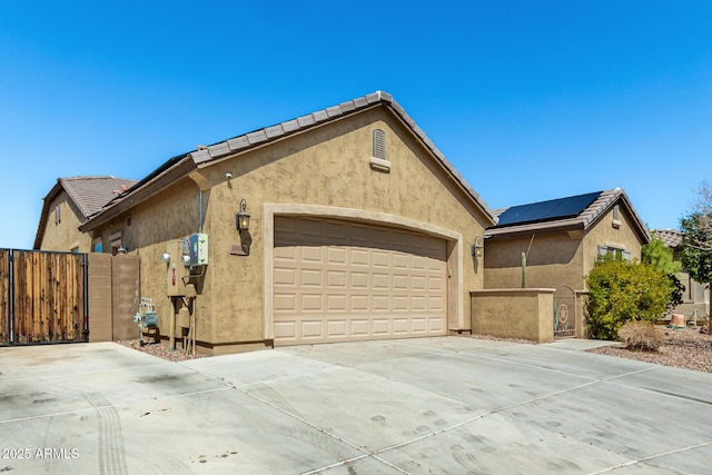 view of side of home with stucco siding, driveway, and a gate