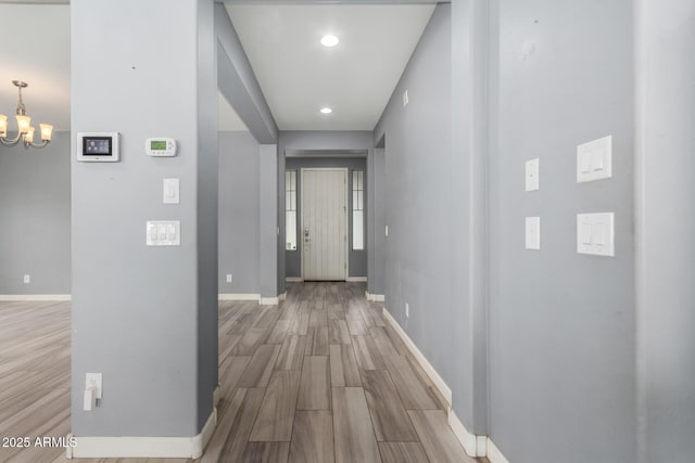 hall with recessed lighting, baseboards, an inviting chandelier, and wood finished floors