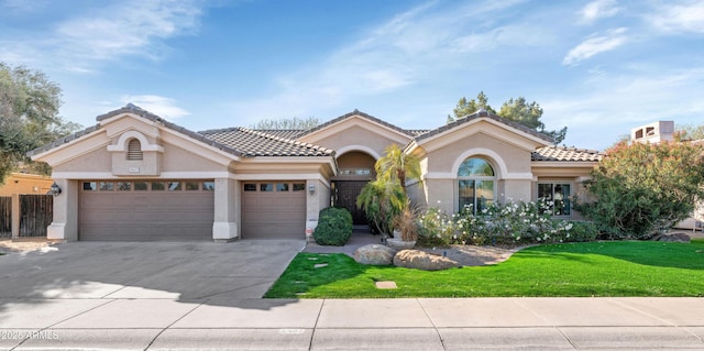 mediterranean / spanish-style home with a garage, concrete driveway, a tiled roof, stucco siding, and a front yard