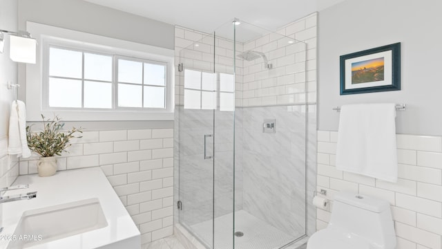 full bath featuring a sink, a shower stall, wainscoting, tile walls, and toilet