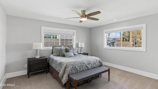 bedroom featuring light colored carpet, a ceiling fan, and baseboards