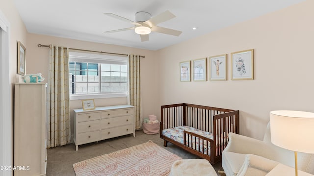 bedroom featuring a crib, carpet, and a ceiling fan