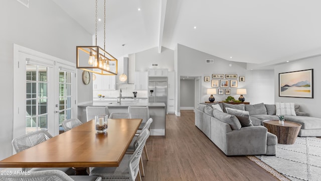 dining space featuring beam ceiling, wood finished floors, visible vents, and high vaulted ceiling