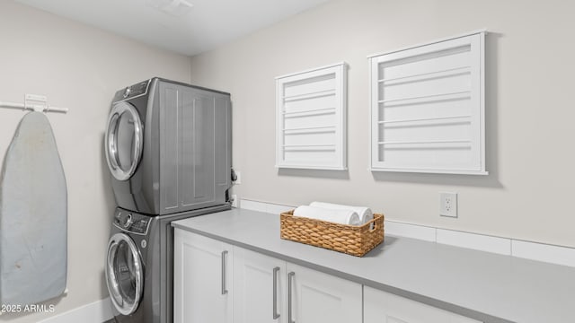 washroom with cabinet space and stacked washer / drying machine