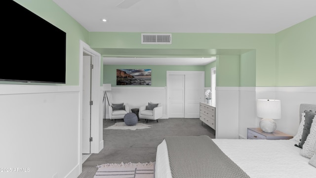 carpeted bedroom with visible vents, a closet, and wainscoting