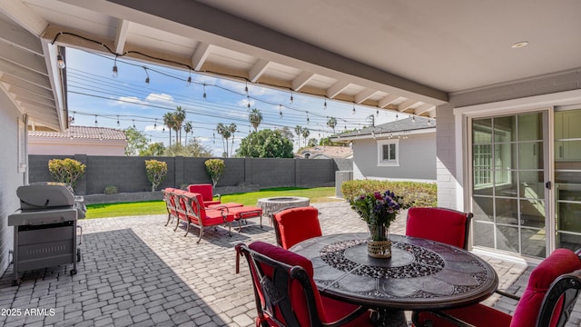 view of patio / terrace with grilling area, a fire pit, outdoor dining area, and a fenced backyard