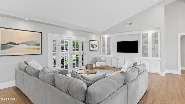 living room with visible vents, baseboards, built in features, light wood-style flooring, and high vaulted ceiling