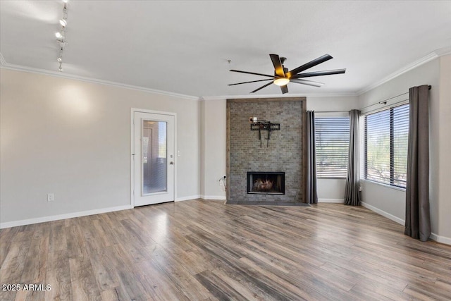 unfurnished living room with track lighting, wood finished floors, ornamental molding, baseboards, and a ceiling fan