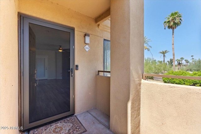 entrance to property with stucco siding and a balcony