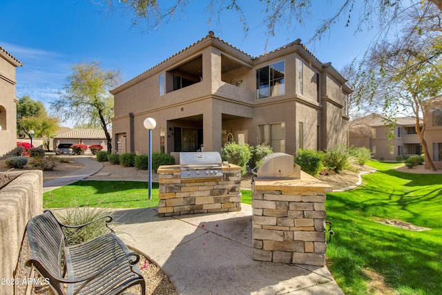 rear view of house featuring area for grilling and a lawn