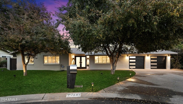 view of front facade featuring a garage, a lawn, and french doors