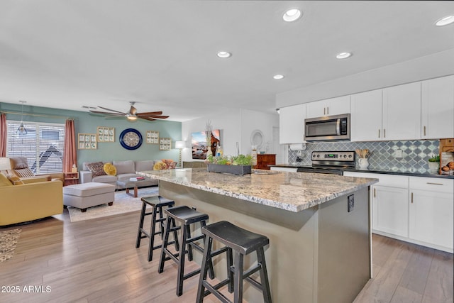 1264 S Sierra St, Gilbert, AZ 85296 - kitchen featuring appliances with stainless steel finishes, open floor plan, a breakfast bar area, a center island, and light wood finished floors