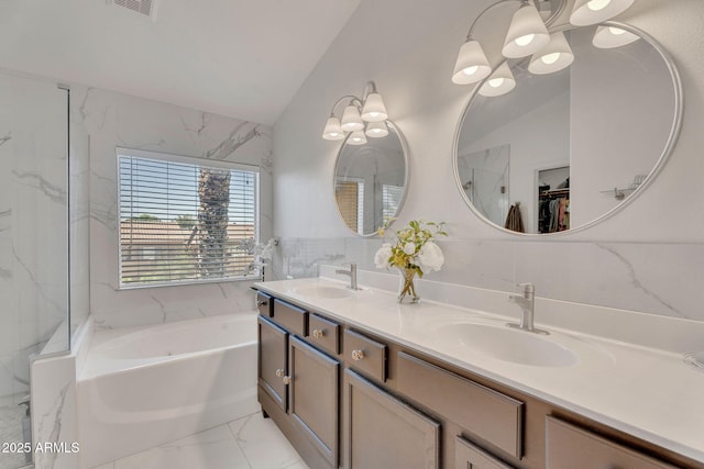 1264 S Sierra St, Gilbert, AZ 85296 - bathroom featuring tile walls, marble look tiles, a bath, double vanity, and a chandelier