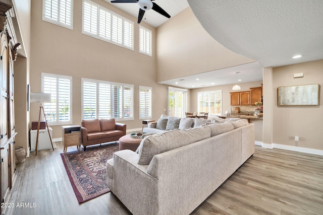 living room featuring ceiling fan, light hardwood / wood-style flooring, and sink