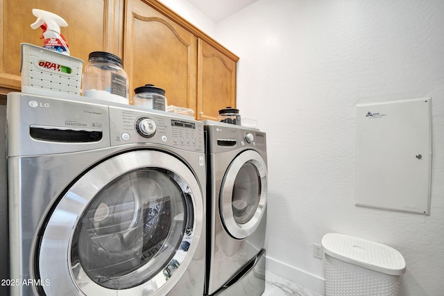 clothes washing area featuring washer and clothes dryer and cabinets