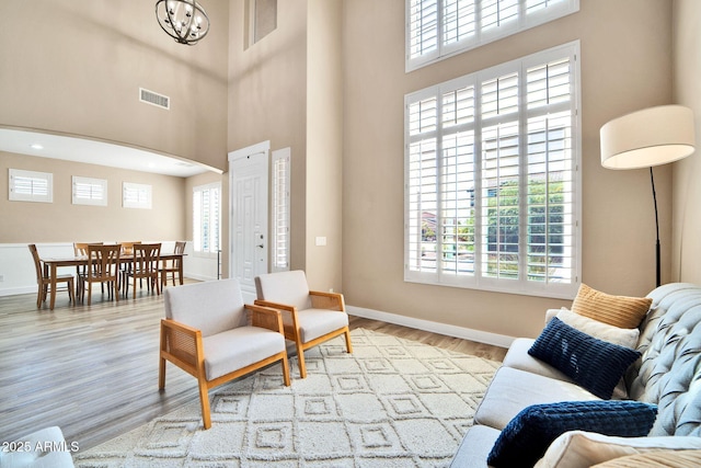 living room with a high ceiling, light wood-type flooring, and an inviting chandelier