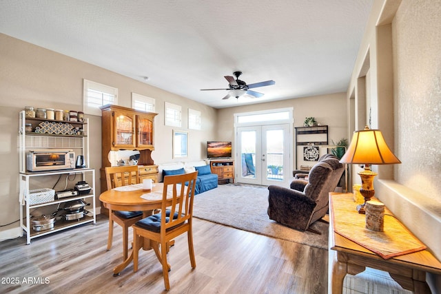 dining room featuring french doors, light hardwood / wood-style floors, ceiling fan, and a healthy amount of sunlight