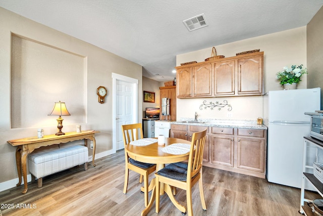 dining room featuring a textured ceiling, light hardwood / wood-style floors, and sink