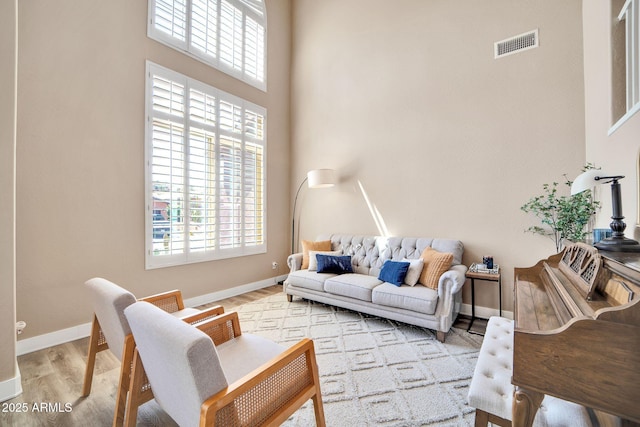 living room with light hardwood / wood-style flooring and a high ceiling