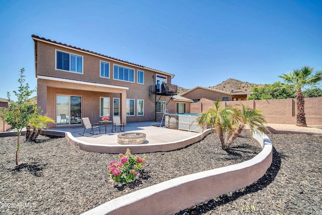 rear view of house featuring a fenced in pool, a patio area, and an outdoor fire pit