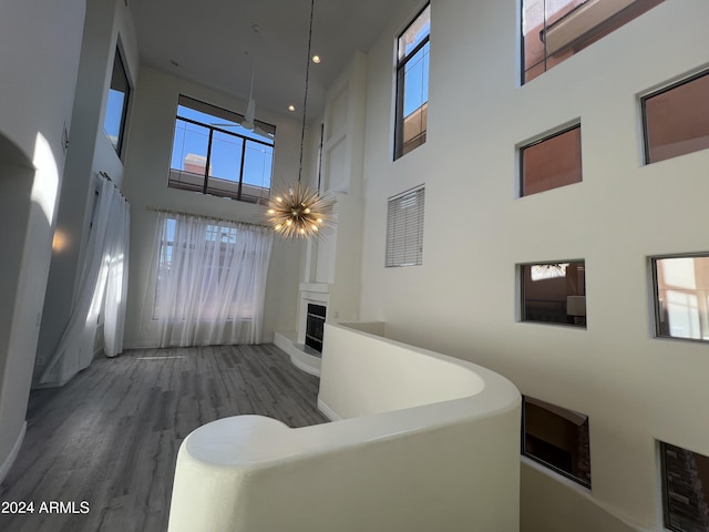 hallway with wood-type flooring, a towering ceiling, and an inviting chandelier