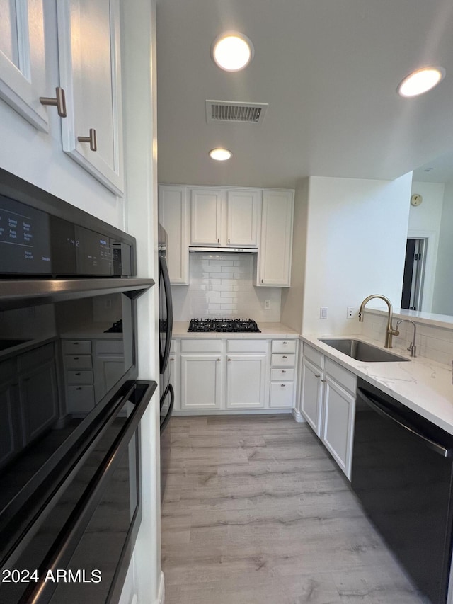 kitchen with white cabinetry, light wood-type flooring, sink, and black appliances