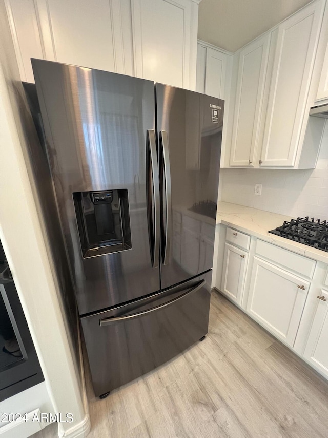 kitchen featuring black gas cooktop, stainless steel fridge, light hardwood / wood-style floors, and white cabinets