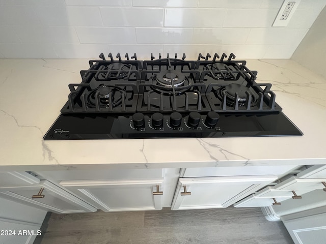 details featuring light stone countertops, decorative backsplash, and black gas cooktop