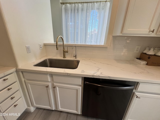 kitchen featuring white cabinetry, sink, stainless steel dishwasher, and light stone counters