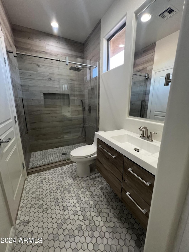 bathroom featuring vanity, a shower with shower door, tile patterned floors, and toilet