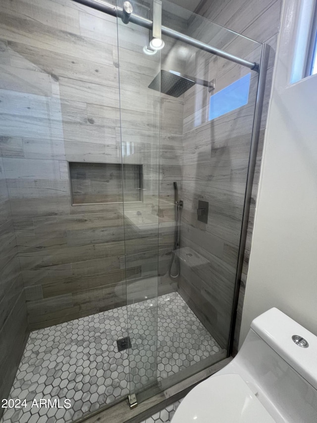 bathroom with toilet and a shower with shower door