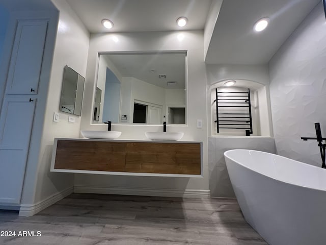 bathroom featuring hardwood / wood-style flooring, vanity, tile walls, and a bathtub