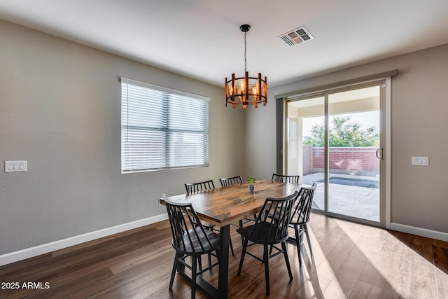 dining area with dark hardwood / wood-style flooring and an inviting chandelier