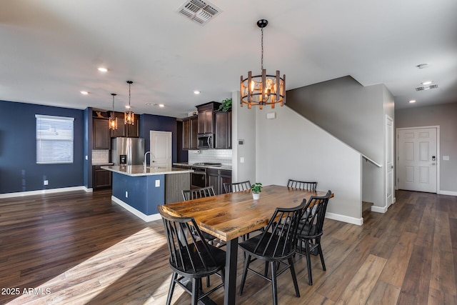 dining room with sink, dark wood-type flooring, and a chandelier