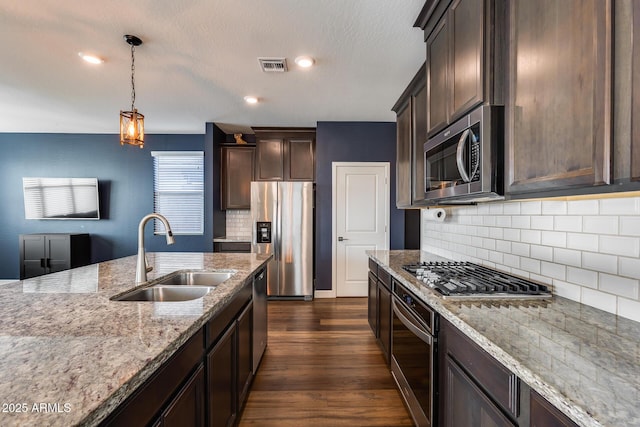 kitchen featuring dark brown cabinetry, light stone countertops, sink, dark hardwood / wood-style floors, and appliances with stainless steel finishes