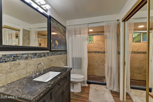 bathroom featuring tile walls, vanity, walk in shower, hardwood / wood-style floors, and toilet