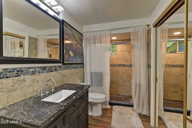 full bathroom with vanity, tile walls, toilet, a stall shower, and wood finished floors
