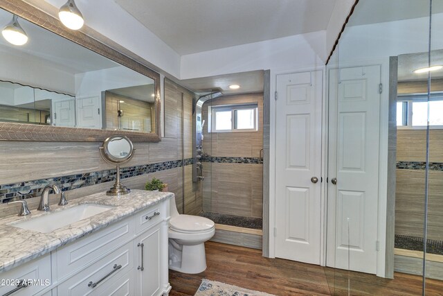 bathroom featuring hardwood / wood-style flooring, walk in shower, vanity, and toilet