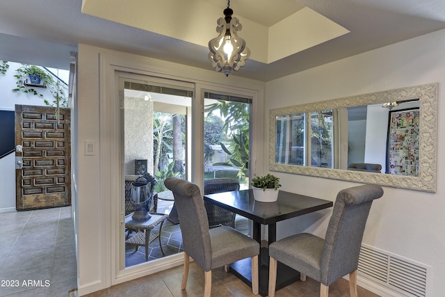 dining room featuring a tray ceiling, visible vents, and tile patterned flooring
