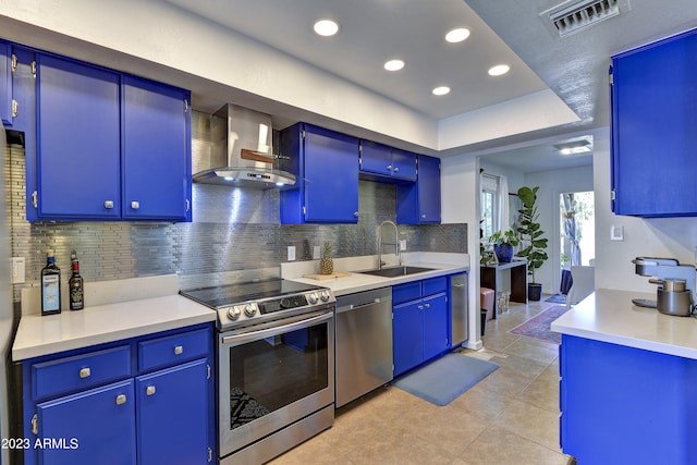 kitchen with blue cabinetry, stainless steel appliances, and wall chimney exhaust hood