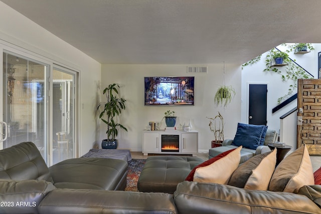 living room featuring baseboards, a textured ceiling, and visible vents