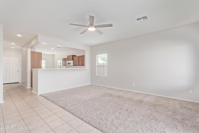 unfurnished living room featuring light carpet and ceiling fan