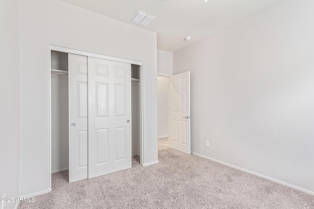 unfurnished bedroom with light carpet and a closet