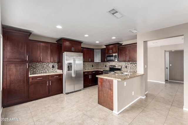 kitchen featuring kitchen peninsula, light stone countertops, tasteful backsplash, appliances with stainless steel finishes, and sink