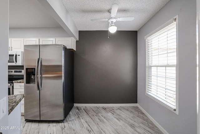 kitchen with a ceiling fan, a textured ceiling, light wood-style floors, white cabinetry, and appliances with stainless steel finishes