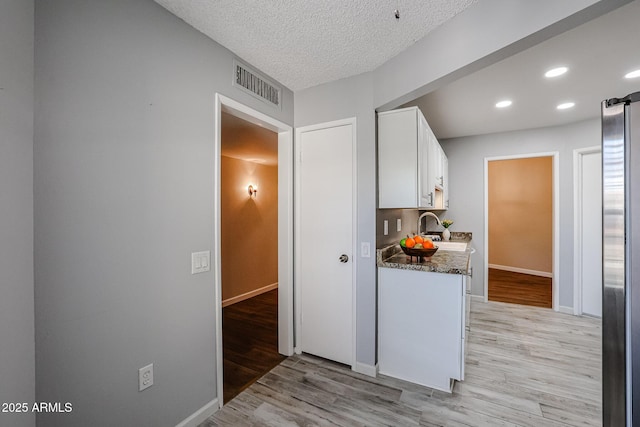 corridor with recessed lighting, light wood-style floors, visible vents, and baseboards