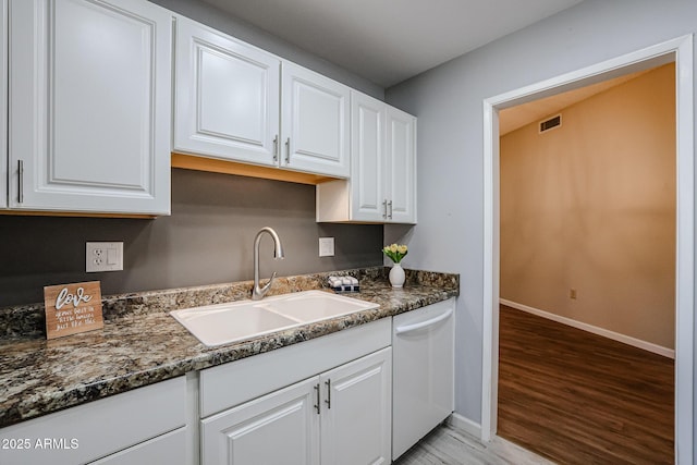 kitchen featuring a sink, dishwasher, light wood-style flooring, baseboards, and white cabinetry