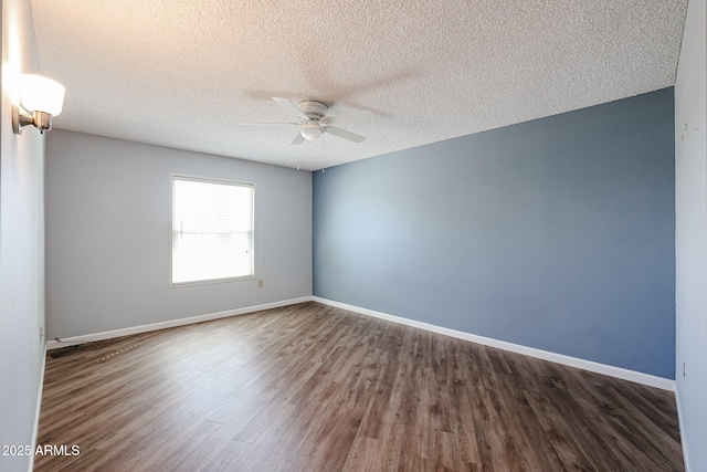 spare room with a textured ceiling, a ceiling fan, baseboards, and dark wood-style flooring