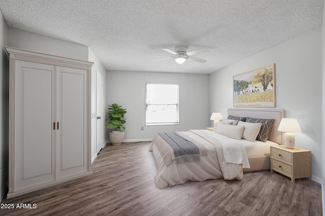 bedroom featuring baseboards, wood finished floors, and ceiling fan