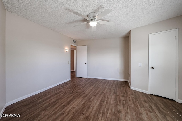 empty room with a textured ceiling, a ceiling fan, baseboards, and dark wood-style flooring